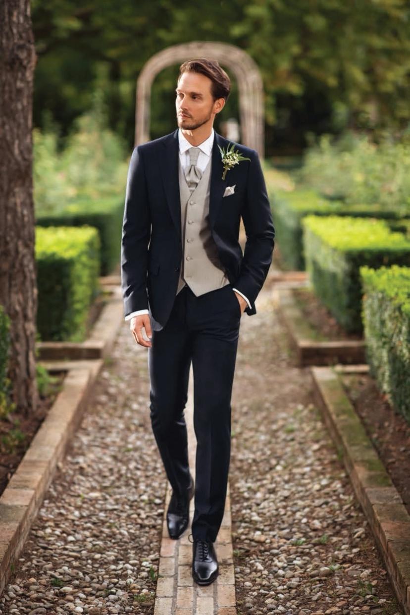 Man in ceremony suit on an alley between greenery